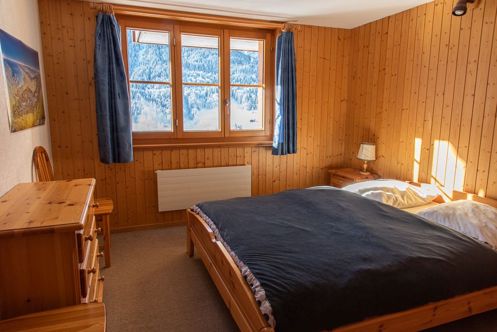 Gemütliches Schlafzimmer mit Holzverkleidung und Bergblick