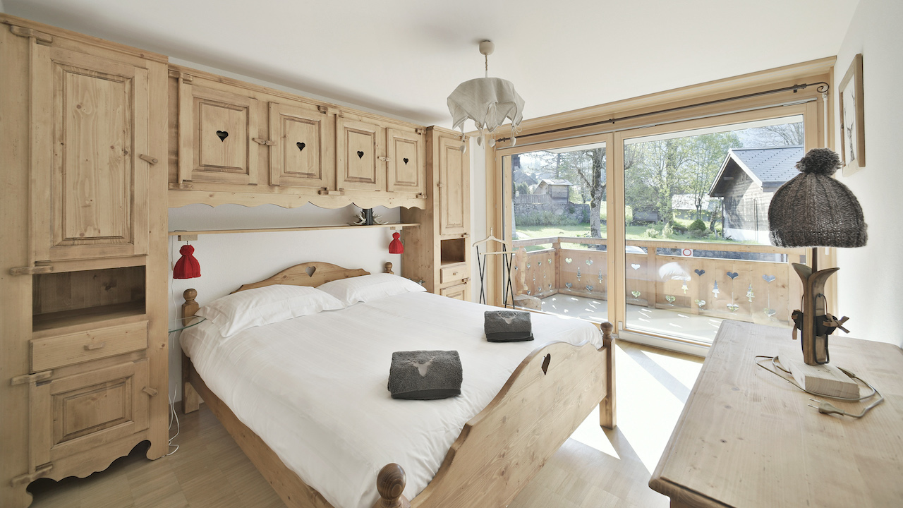 Rustikales Schlafzimmer mit Holzinterieur und Balkonblick
