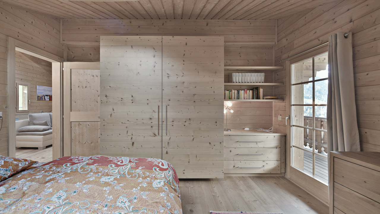 Gemütliches Holzschlafzimmer mit Kleiderschrank und Balkonblick