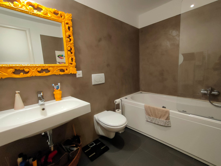 Modernes Badezimmer mit Badewanne und auffälligem goldenen Spiegelrahmen