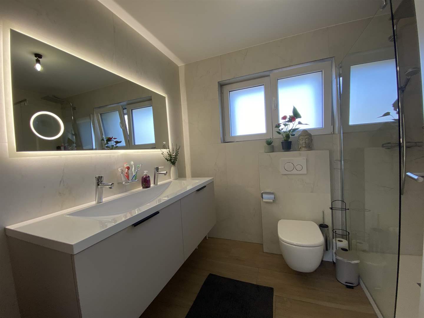 Modernes Badezimmer mit Doppelwaschtisch, WC und bodentiefer Glasdusche