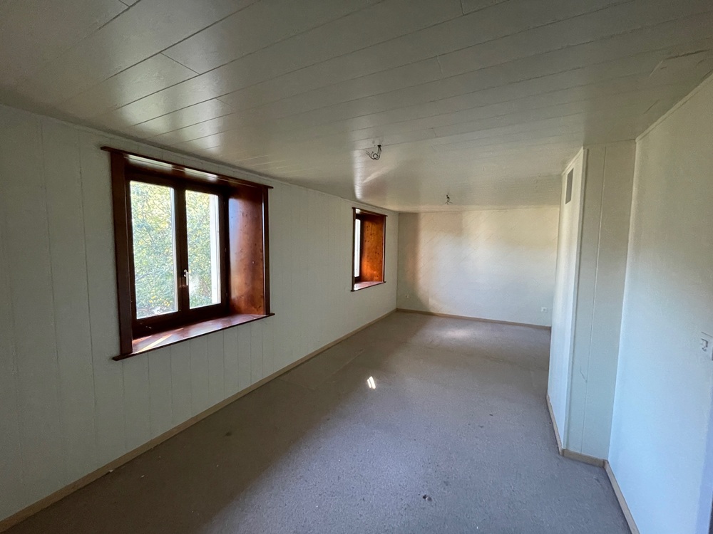Langer leerer Raum mit zwei Holzfenstern