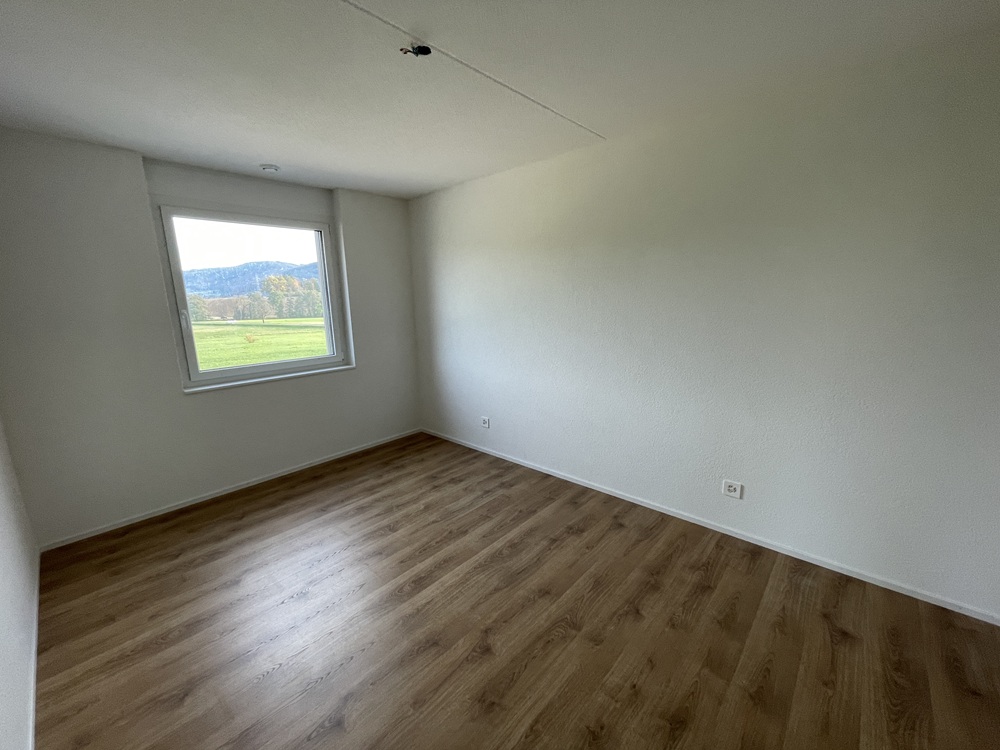 Leeres Zimmer mit Fenster und Holzoptik-Boden