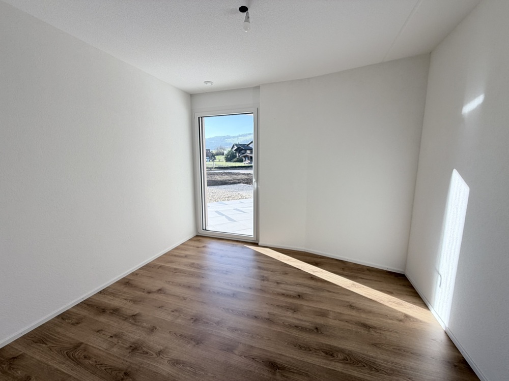 Heller leerer Raum mit Holzboden und Tür zum Außenbereich