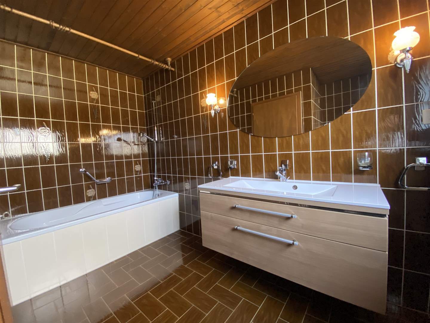 Badezimmer mit brauner Fliesenoptik und Holzdecke