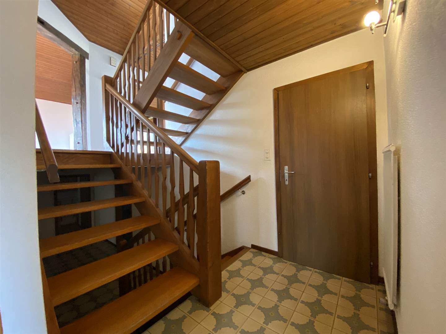 Treppenhaus mit Holztreppe und Fliesenboden