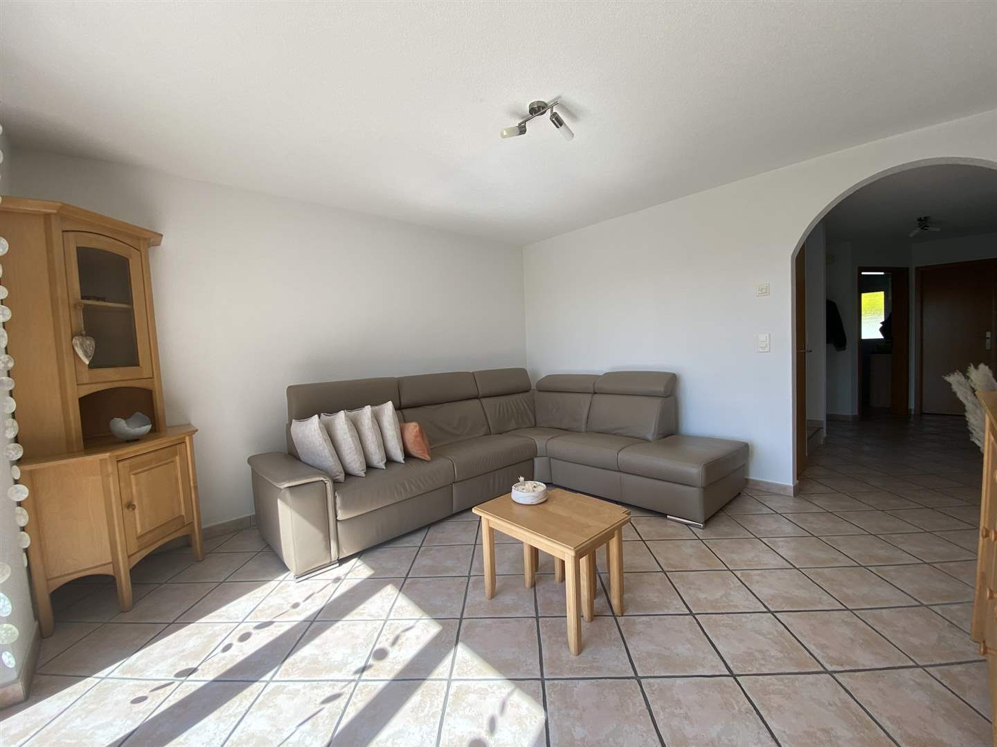 Helles Wohnzimmer mit Ecksofa und Vitrine
