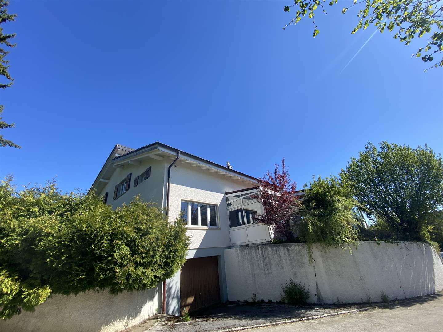 Wohnhaus mit weißer Fassade und Gartenumgebung