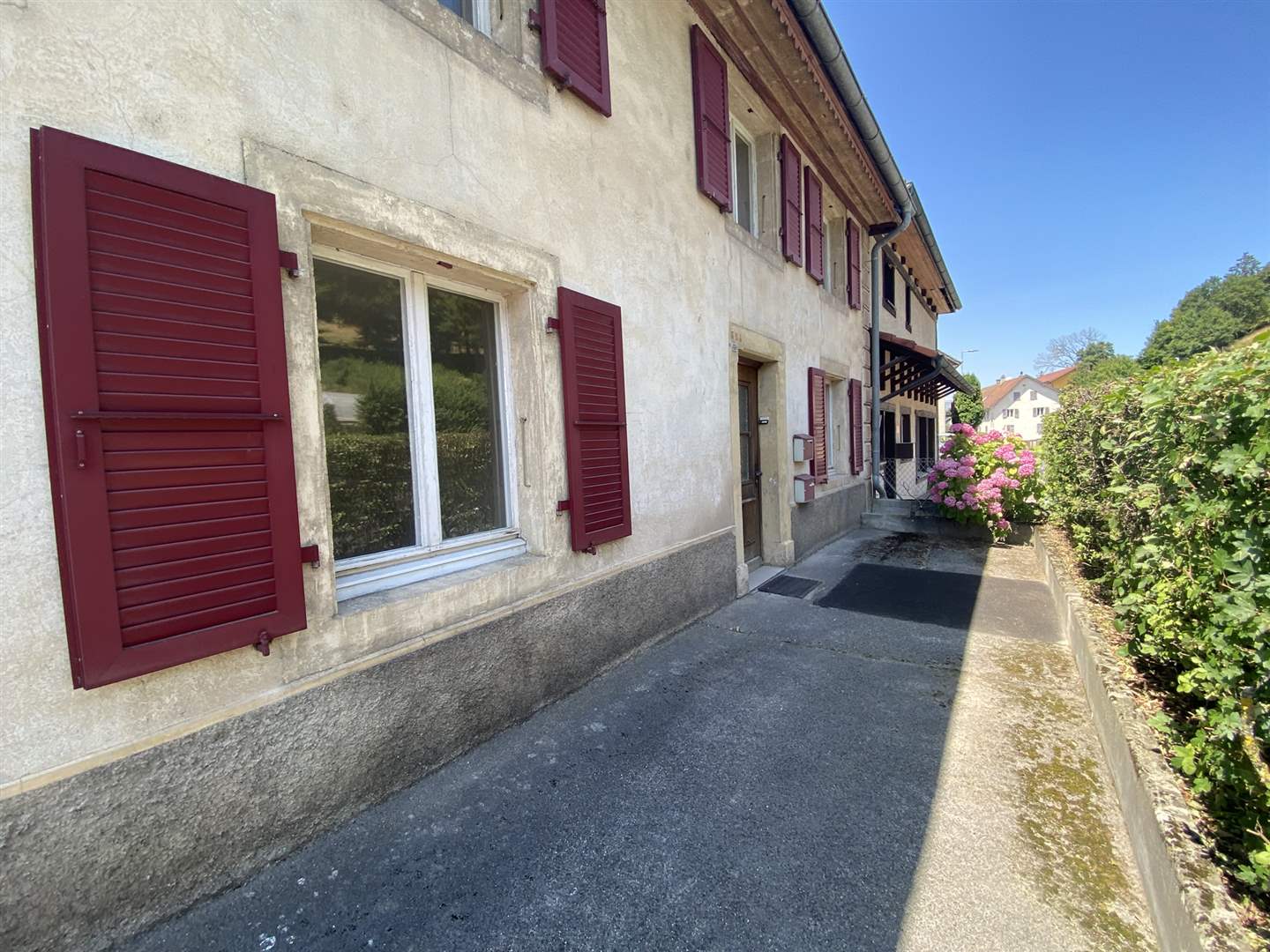 Hausfassade mit Fensterläden und Gartenweg