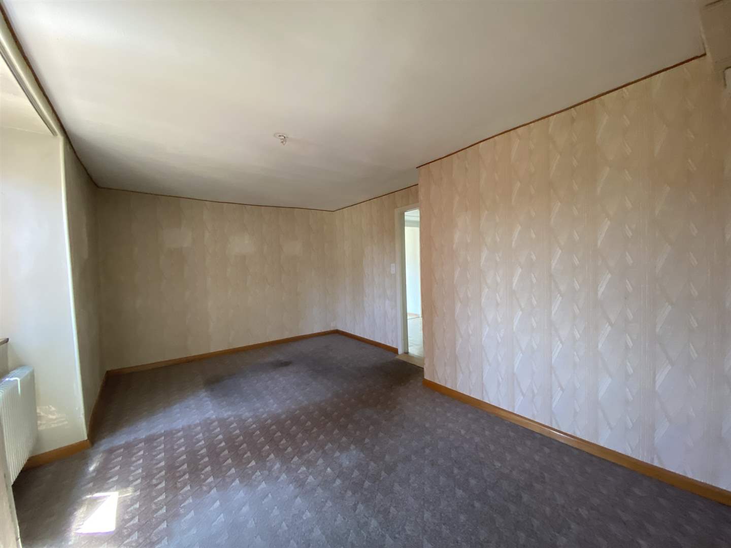 Leerer Wohnraum mit Tapete und Teppichboden