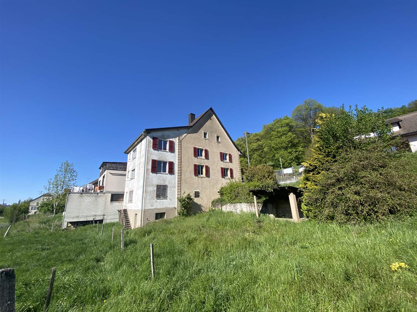 Außenansicht eines älteren Wohnhauses mit Gartenhang