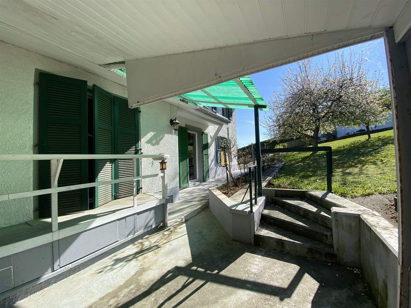 Überdachter Außenbereich mit Treppe und Blick ins Grüne