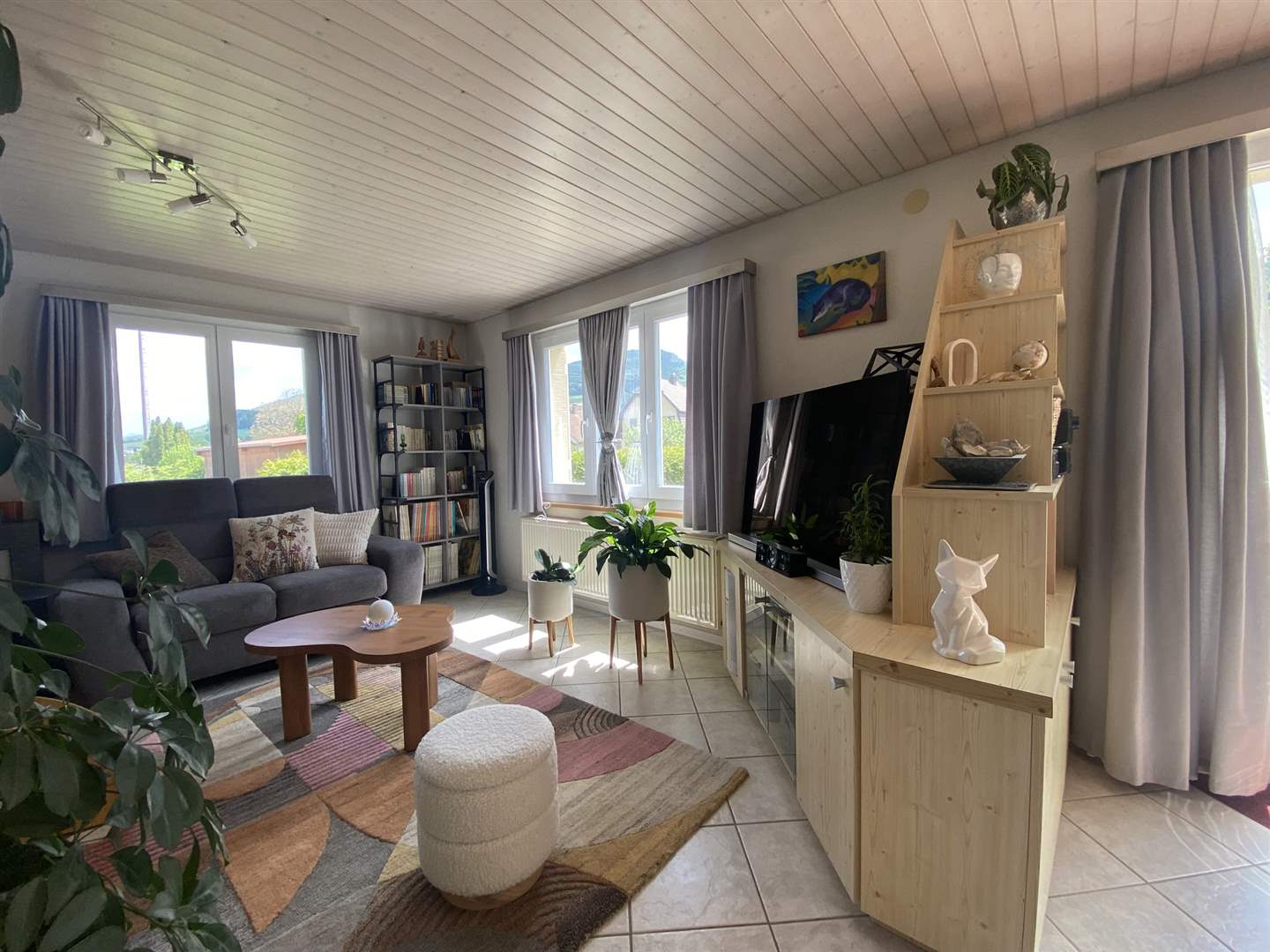 Helles Wohnzimmer mit Fensterfront und Regalwand