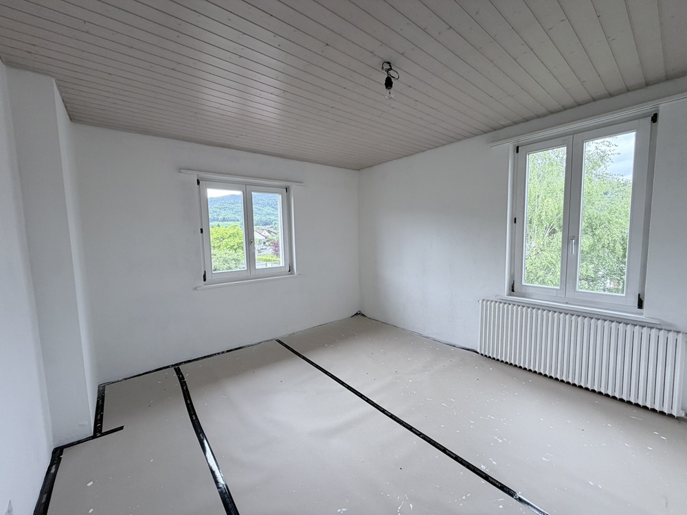 Leerer heller Raum mit zwei Fenstern und Heizkörper
