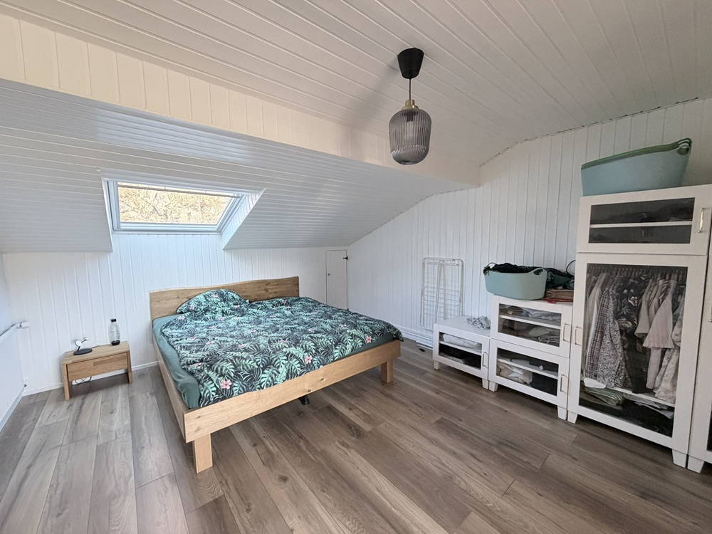 Dachgeschoss-Schlafzimmer mit Holzoptik und Dachfenster