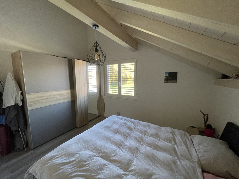 Dachgeschoss-Schlafzimmer mit sichtbaren Holzbalken