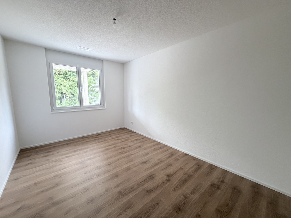 Leerer Raum mit Fenster und Holzoptik-Boden