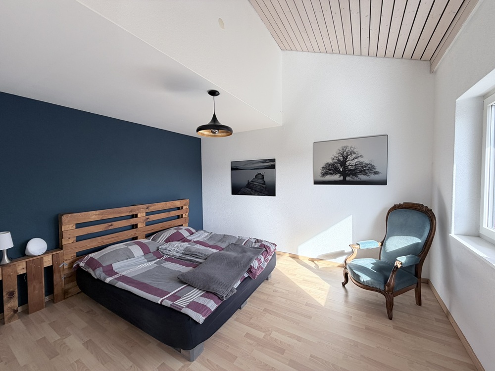 Helles Schlafzimmer mit Holzbett und blauem Akzent