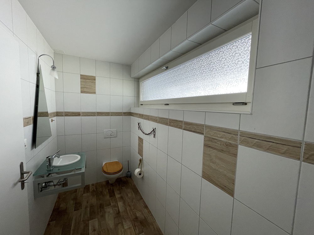 Kleines helles Gäste-WC mit Fliesen und Holzoptik