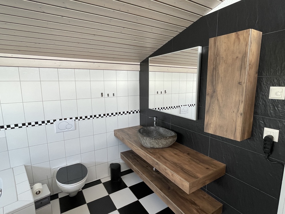 Modernes Gäste-WC mit dunkler Akzentwand und Holzdetails