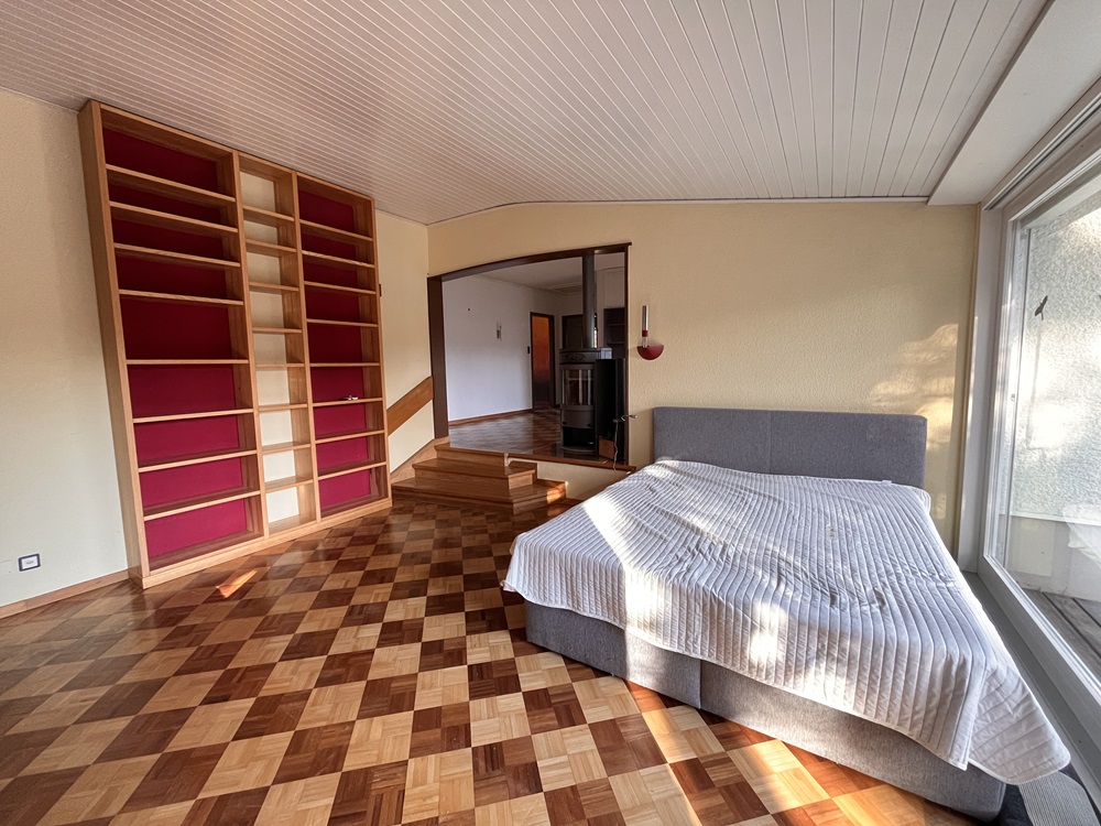 Schlafzimmer mit Holzparkett und großem Fenster