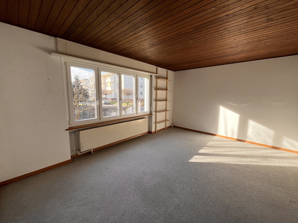 Leerer Wohnraum mit Holzdecke und großem Fenster