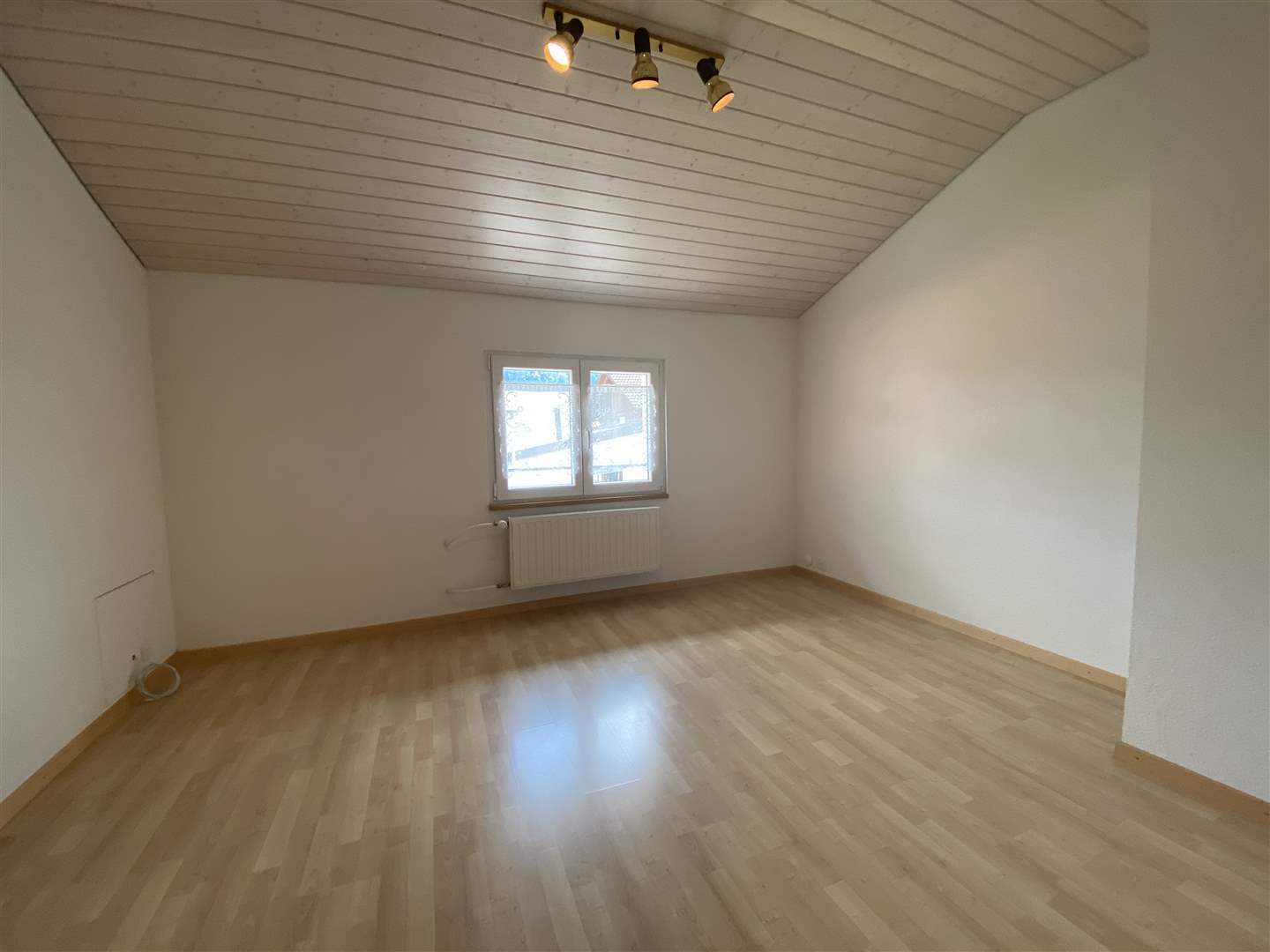 Leerer Dachgeschossraum mit Holzdecke und Fenster