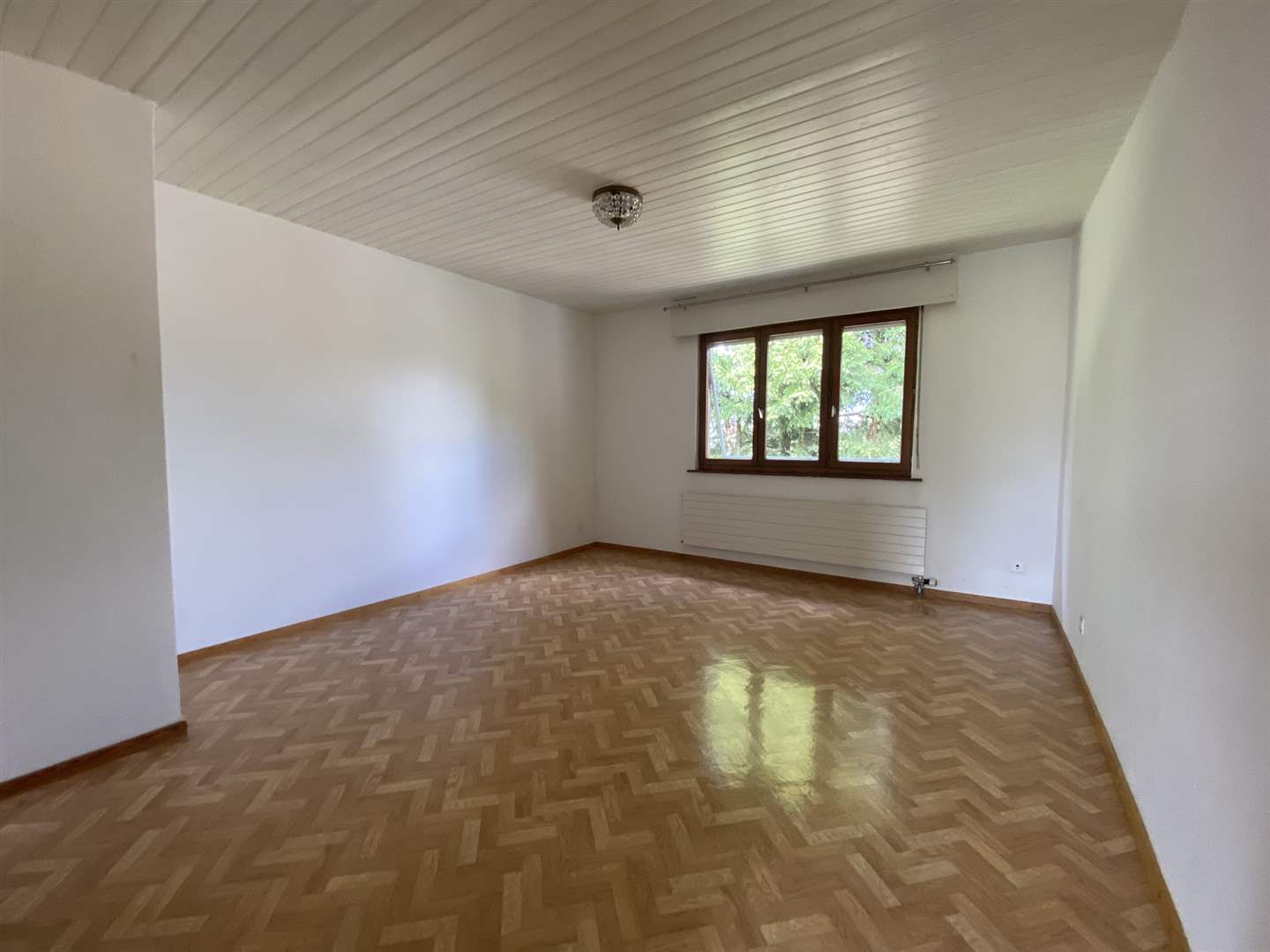 Leerer Wohnraum mit Fenster und Parkettboden