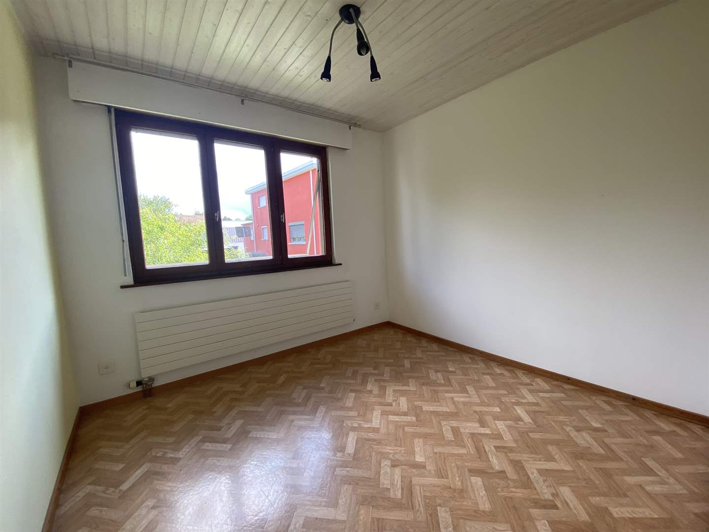 Leerer heller Raum mit Parkett und Fenster