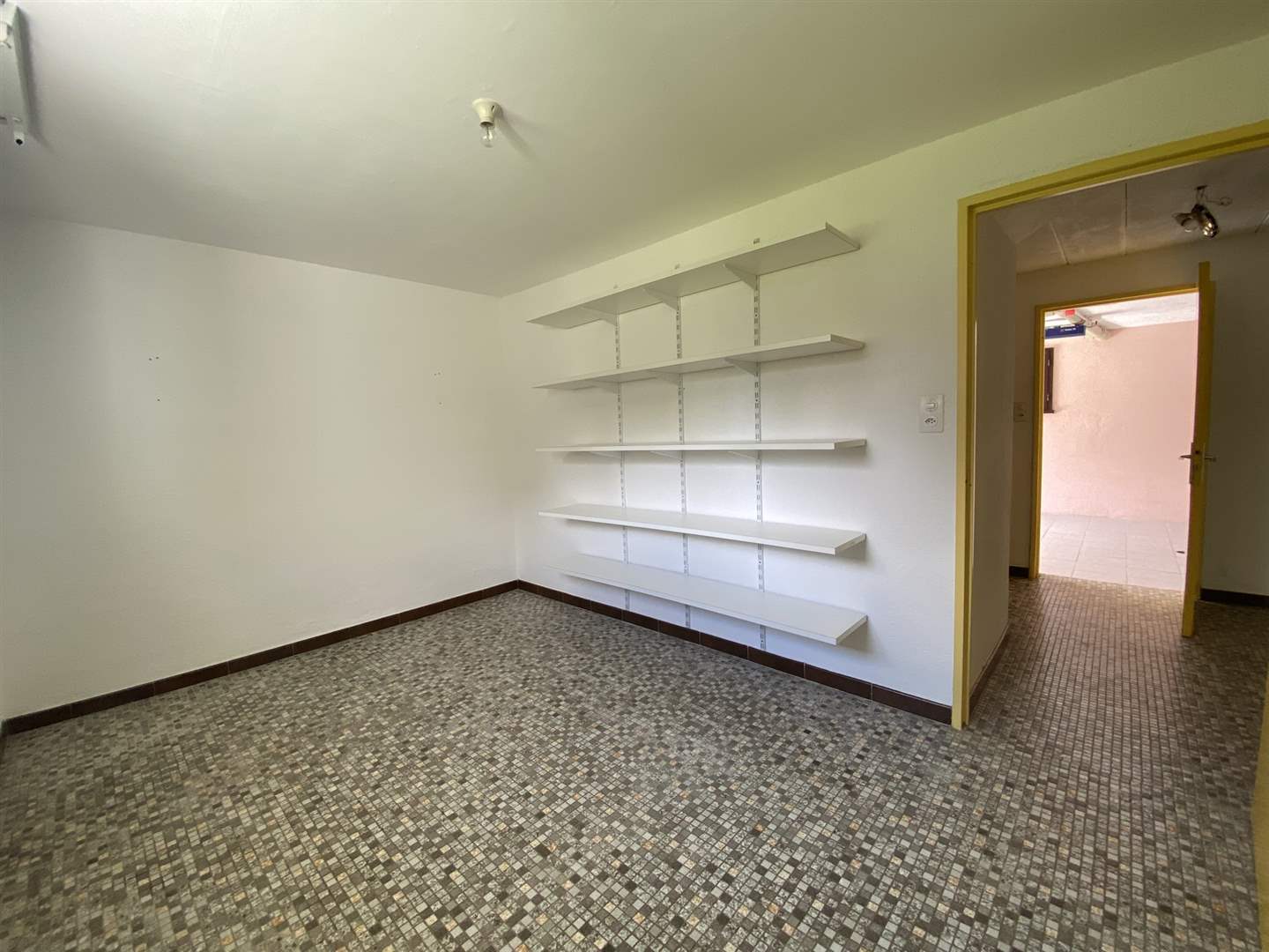 Leerer Nutzraum mit Fliesenboden und Regalen