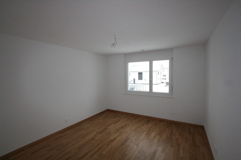 Leeres, helles Zimmer mit Holzboden und Fenster