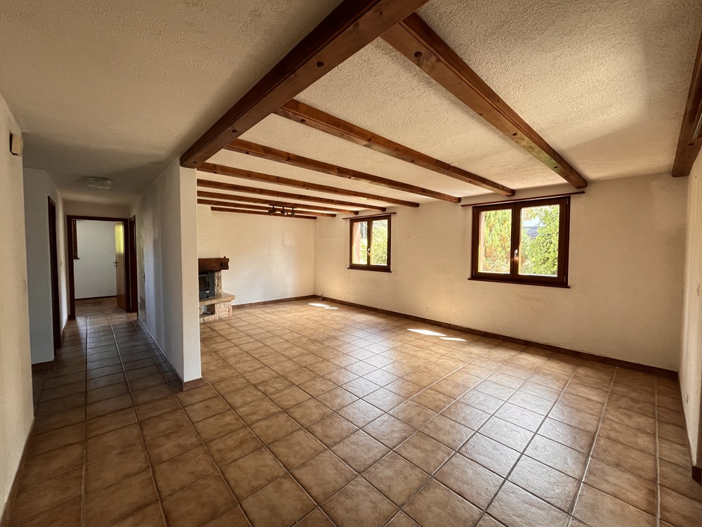 Wohnraum mit sichtbaren Holzbalken und Fliesenboden