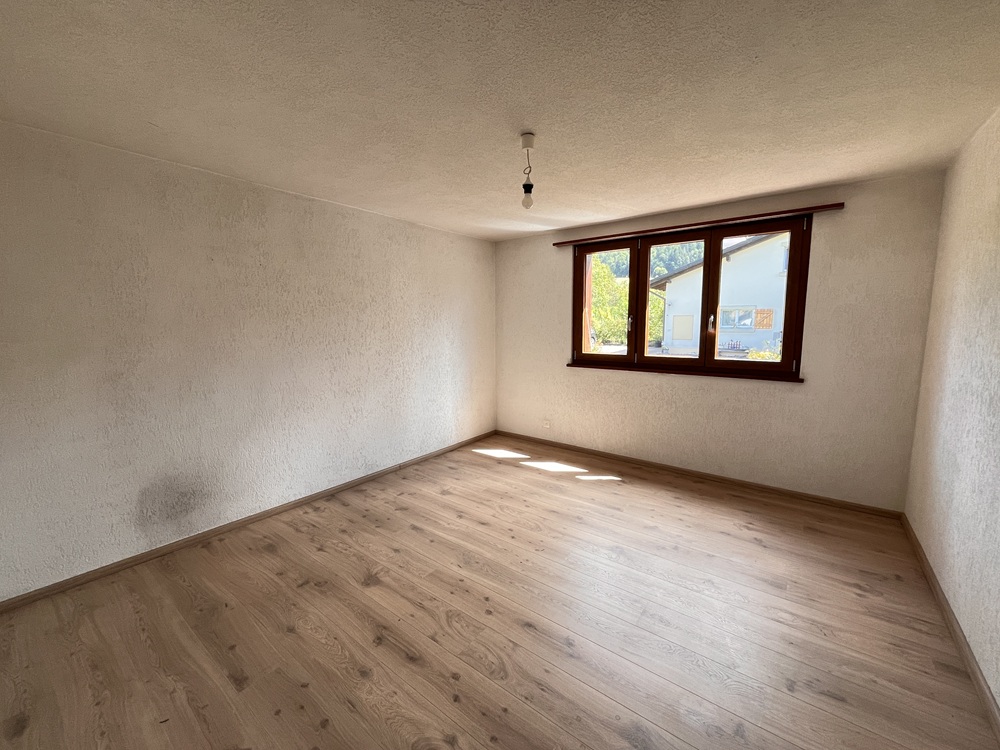 Heller leerer Raum mit Holzoptik-Boden und Fenster