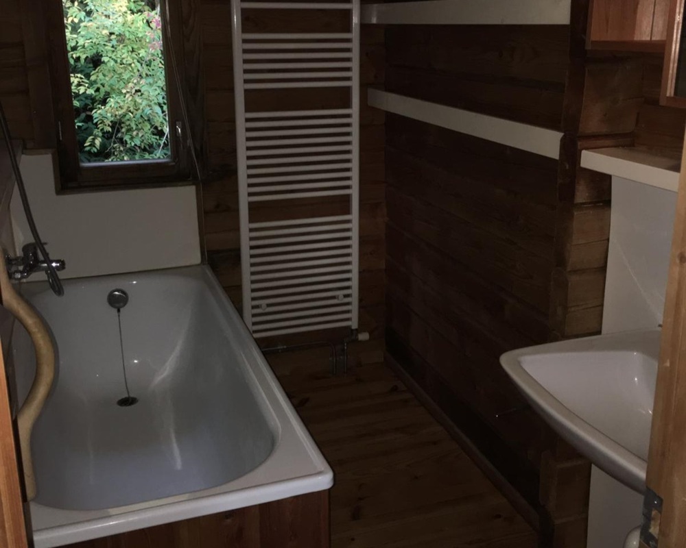 Kleines Bad mit Badewanne und Holzverkleidung