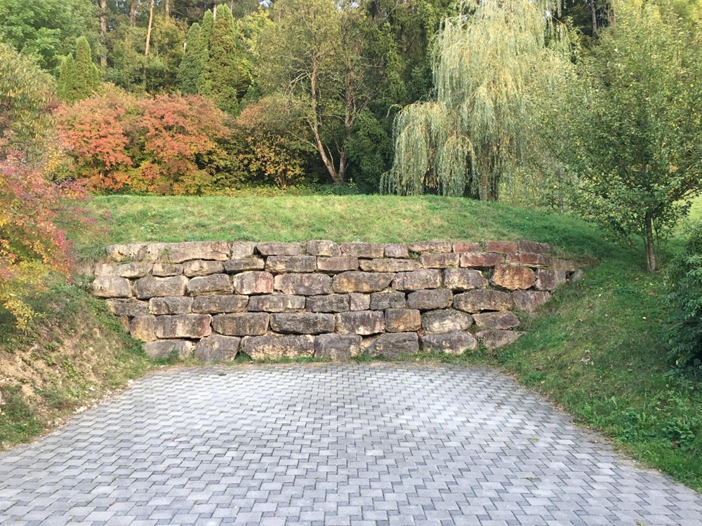 Gartenbereich mit Stützmauer und gepflasterter Fläche