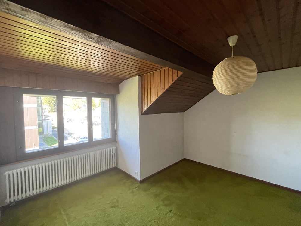 Leerer Raum mit Holzdecke und grünem Teppichboden