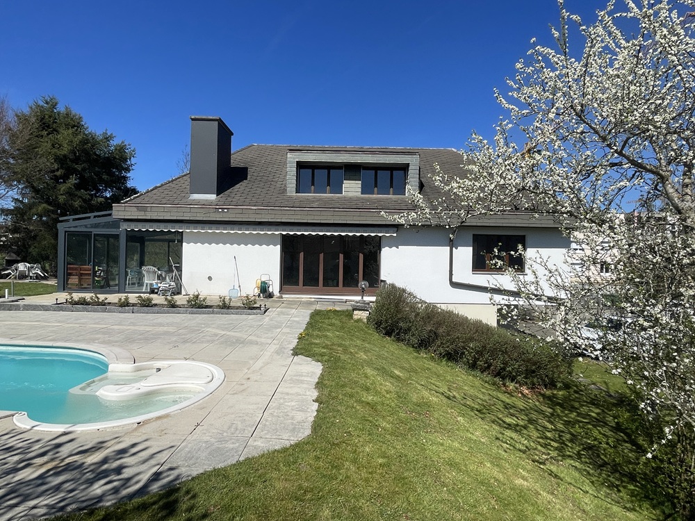 Außenansicht eines Einfamilienhauses mit Pool und Garten