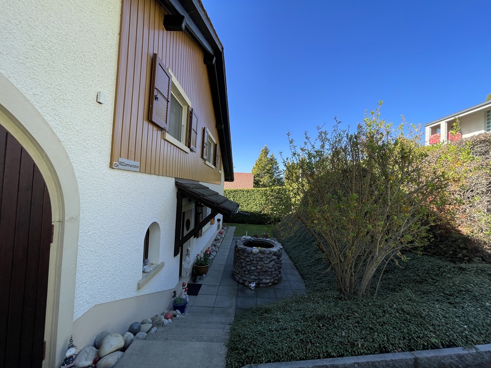 Hausaußenansicht mit Gartenweg und Brunnen
