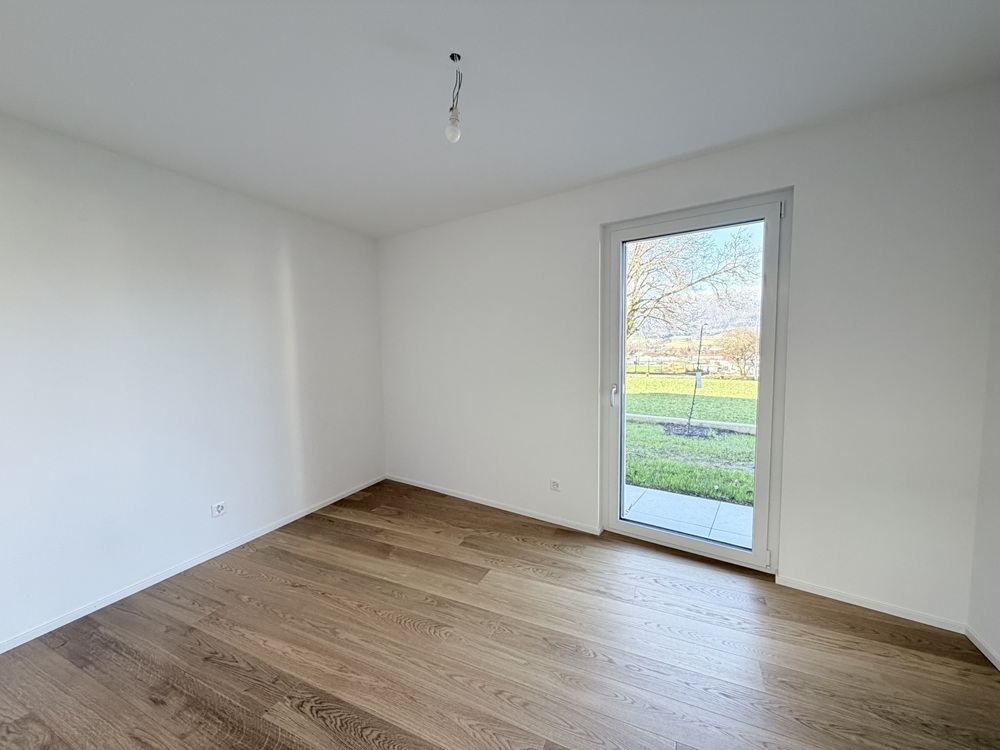 Leerer heller Raum mit Holzboden und Terrassentür