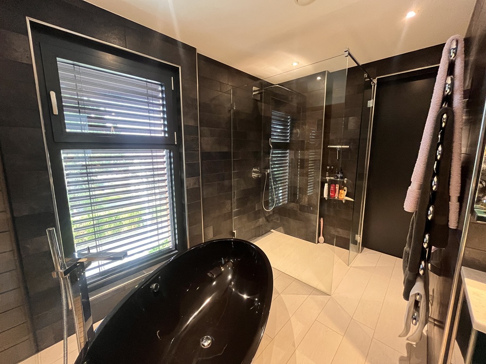 Modernes Badezimmer mit dunklen Fliesen und Badewanne