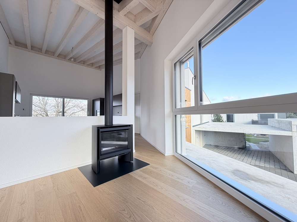 Offener Wohnbereich mit Kamin und großer Fensterfront