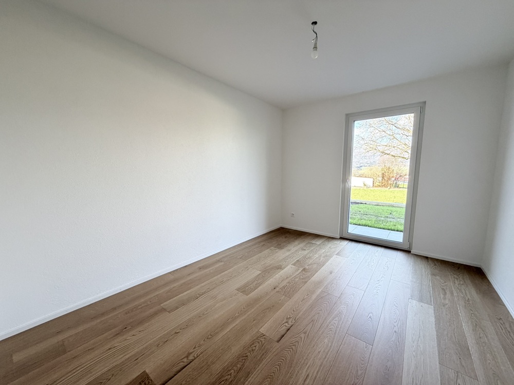 Leerer heller Raum mit Holzboden und Tür zum Garten