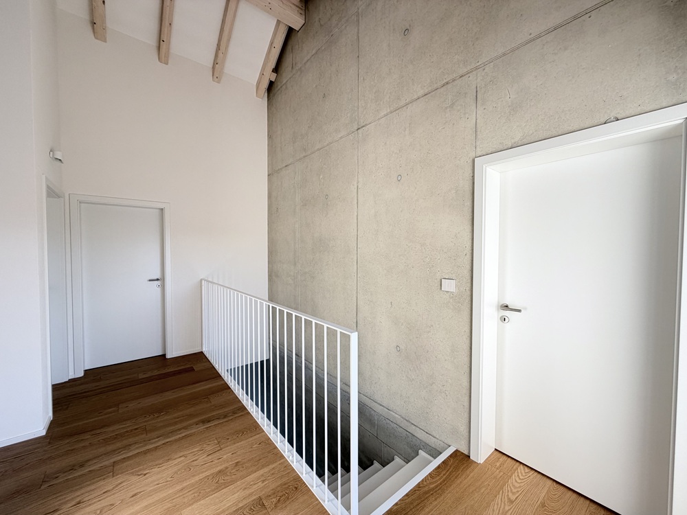 Offener Flurbereich mit Treppe und Sichtbetonwand