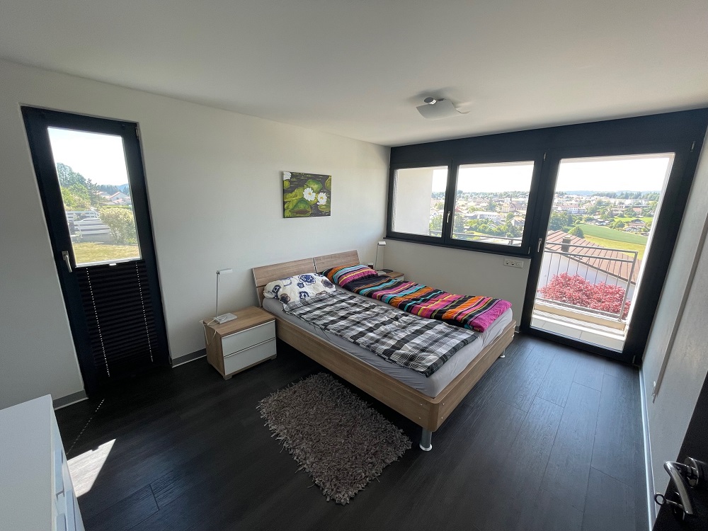 Schlafzimmer mit Panoramafenstern und Balkon