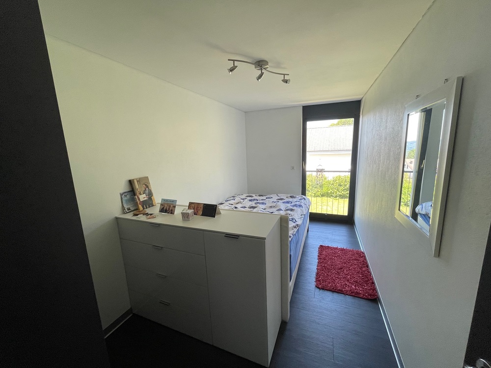 Schmales Schlafzimmer mit Bett und Fenster zum Garten