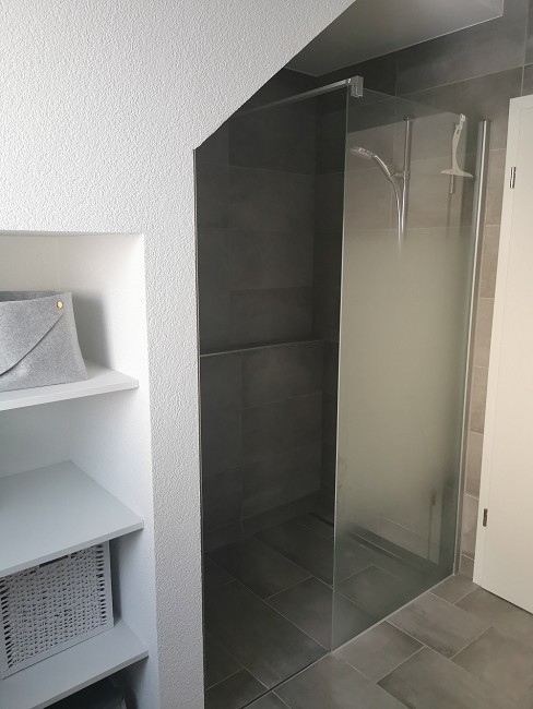 Badezimmer mit Glasdusche und Ablagewand