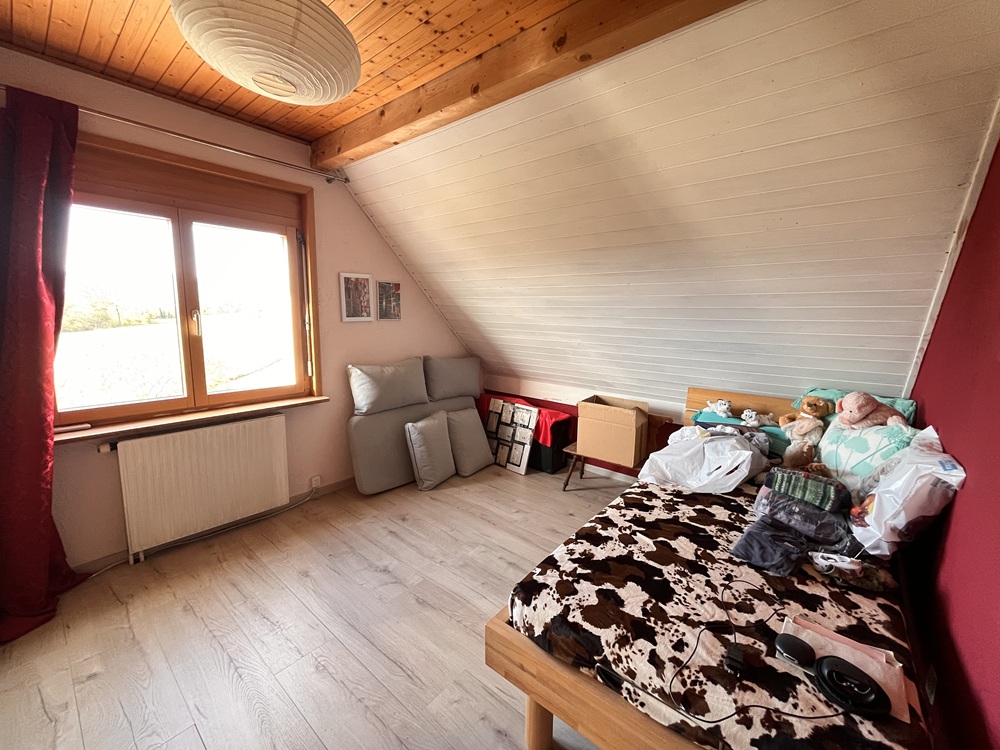 Dachzimmer mit Bett und Fenster