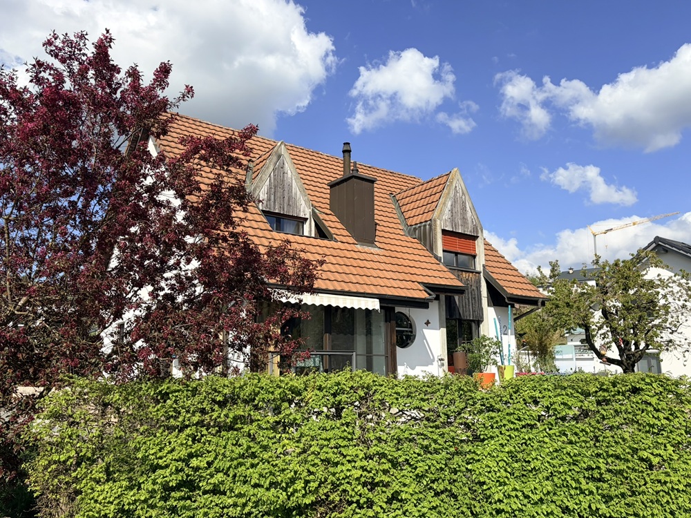 Außenansicht eines Hauses mit Satteldach und Gartenhecke