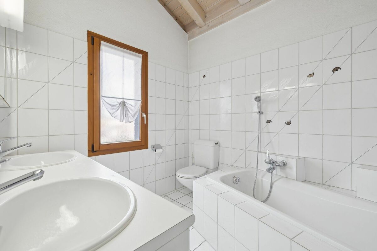 Helles Badezimmer mit Badewanne, Waschtisch und Holzfenster