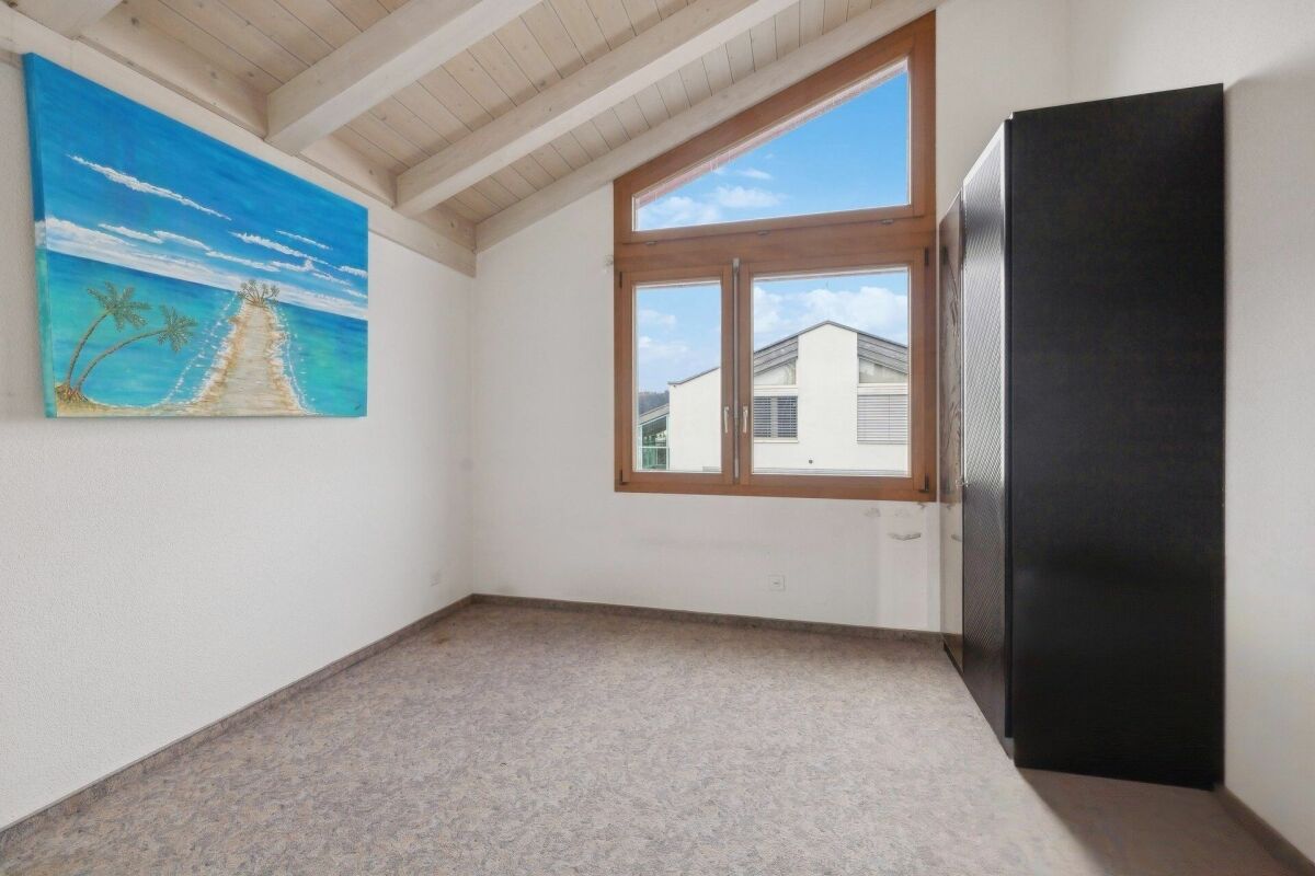 Heller Raum mit Dachschräge und großem Fenster